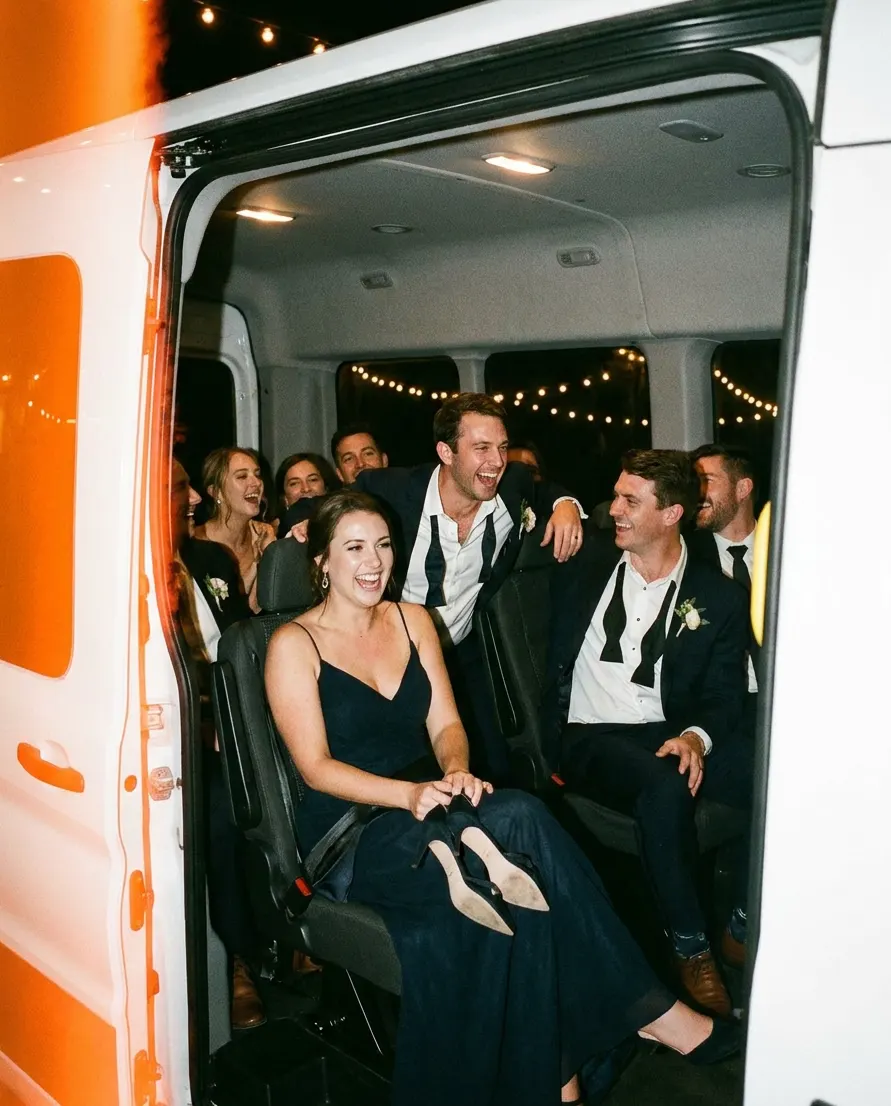 Guests laughing in the back of a wedding shuttle van.